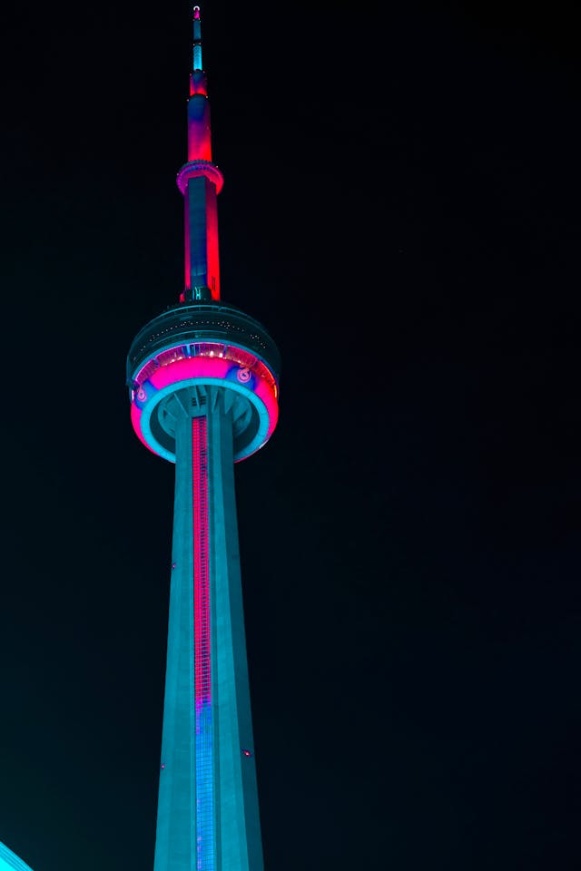 The CN tower with Toronto Raptor colors to highlight the question is hiring Bobby Webster the right decision.